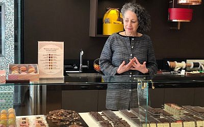 Rabbi Deborah Prinz points on front of a display of different chocolates at La Maison du Chocolat, perhaps the holiest site for cocoa lovers on the Upper East Side (Danielle Ziri/ Times of Israel)