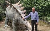 Dr. Evgeny Reznitsky, educational director of the Natural History Museum in Jerusalem, standing next to a dinosaur statue in the museum's outer garden on May 1, 2018. (Michael Bachner/Times of Israel)