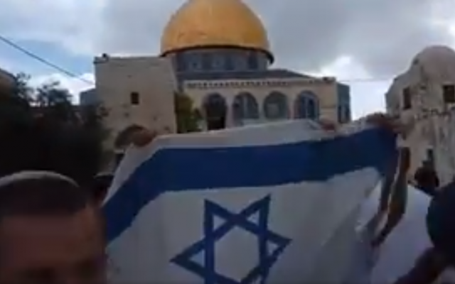 Jewish youth raising an Israeli flag at the Temple Mount in Jerusalem's Old City on Jerusalem Day, May 13, 2018. (Screen capture: YouTube)