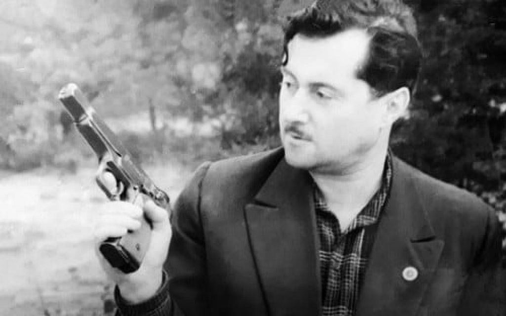 Joseph Schneider holds a pistol. (Courtesy National Library of Israel)