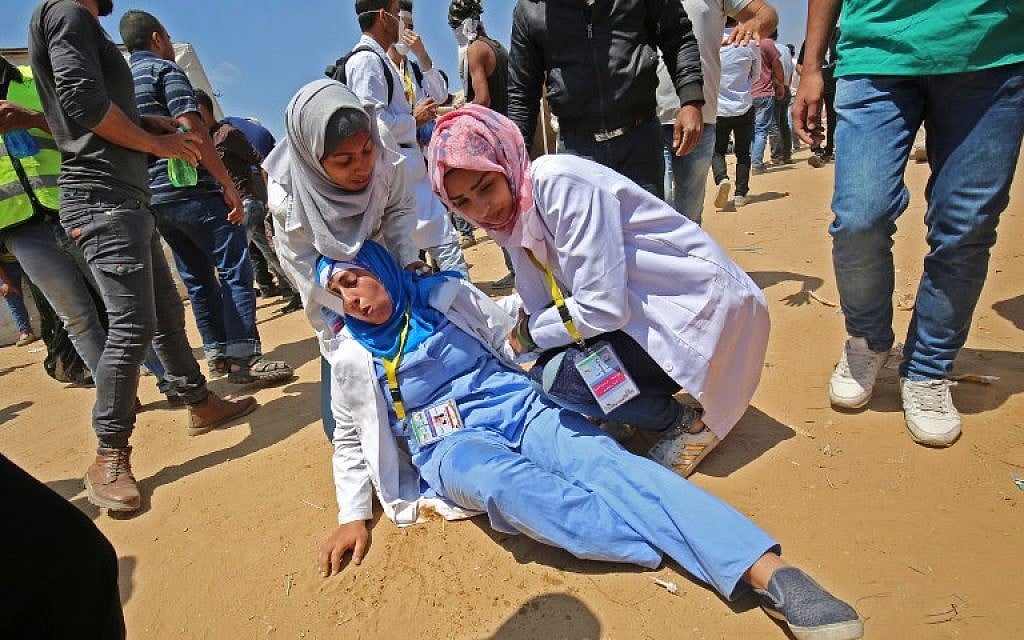 Razan al-Najjar (R), a 21-year-old Palestinian paramedic, tends to an injured colleague, during clashes near the border with Israel, east of Khan Yunis in the southern Gaza Strip, on May 15, 2018. (AFP/ SAID KHATIB)
