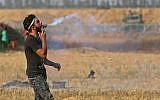 A Palestinian protester holds a tear gas canister in his mouth during a demonstration along the border with Israel east of Khan Yunis in the southern Gaza strip on June 1, 2018. (AFP PHOTO / SAID KHATIB)