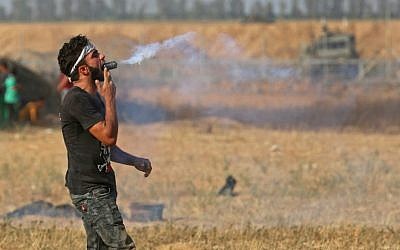 A Palestinian protester holds a tear gas canister in his mouth during a demonstration along the border with Israel east of Khan Yunis in the southern Gaza strip on June 1, 2018. (AFP PHOTO / SAID KHATIB)