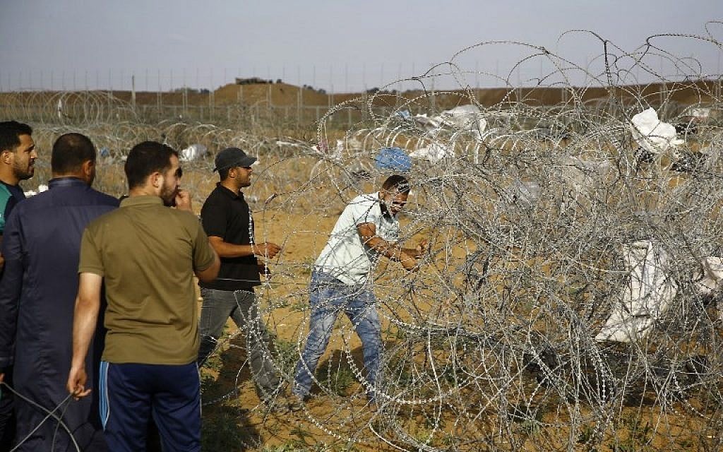 A Palestinan protester cuts a section of barbed wire on the border fence with Israel, east of Jabalia in the central Gaza Strip on June 1, 2018. (AFP PHOTO / Mohammed ABED)