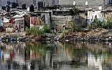 A picture taken on June 1, 2018, shows a girl running past hovels near a sewage water pool at a poor neighborhood in Gaza City. (AFP/Mahmud Hams)