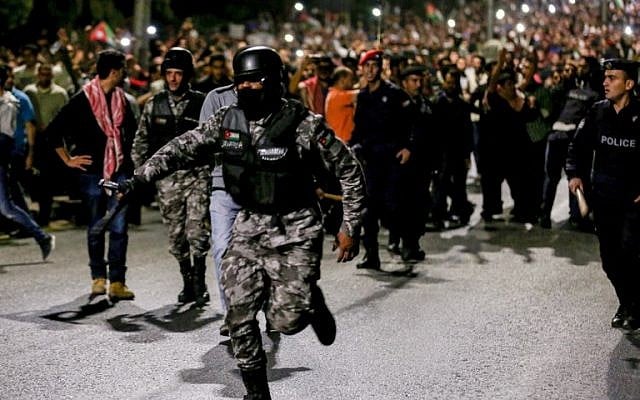 A member of the Jordanian gendarmerie runs as riot police stand on guard before protesters during a demonstration outside the Prime Minister's office in the capital Amman late on June 2, 2018. (AFP PHOTO / Khalil MAZRAAWI) A member of the Jordanian gendarmerie runs as riot police stand on guard before protesters during a demonstration outside the Prime Minister's office in the capital Amman late on June 2, 2018. (AFP PHOTO / Khalil MAZRAAWI)