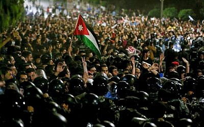 Members of the Jordanian gendarmerie and security forces stand on alert as protesters shout slogans and raise a national flag during a demonstration outside the Prime Minister's office in the capital Amman late on June 2, 2018. (AFP PHOTO / Khalil MAZRAAWI)