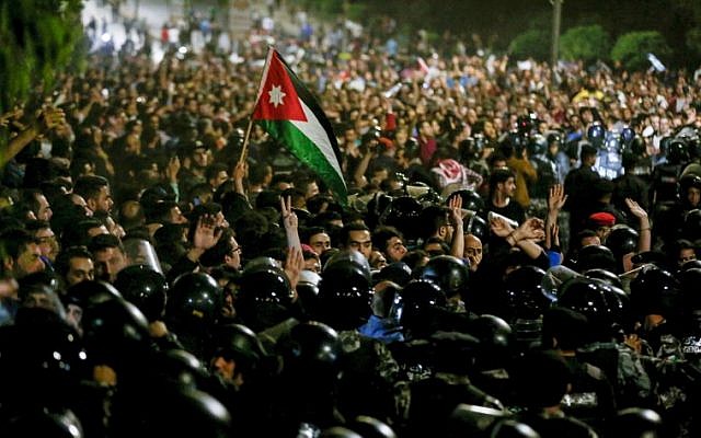 Members of the Jordanian gendarmerie and security forces stand on alert as protesters shout slogans and raise a national flag during a demonstration outside the Prime Minister's office in the capital Amman late on June 2, 2018. (AFP PHOTO / Khalil MAZRAAWI) Members of the Jordanian gendarmerie and security forces stand on alert as protesters shout slogans and raise a national flag during a demonstration outside the Prime Minister's office in the capital Amman late on June 2, 2018. (AFP PHOTO / Khalil MAZRAAWI)