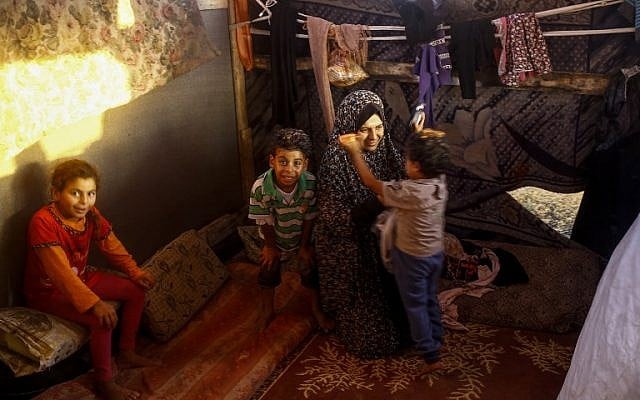A woman sits with her children in their shack home near the beach in Gaza City on June 4, 2018. (MOHAMMED ABED/AFP) A woman sits with her children in their shack home near the beach in Gaza City on June 4, 2018. (MOHAMMED ABED/AFP)