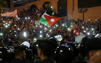 Demonstrators wave Jordanian flags and hold up their lit mobile phones as they face Jordanian police officers during a protest near the prime minister's office in Amman, Jordan, on June 5, 2018. (AFP PHOTO / Khalil MAZRAAWI)
