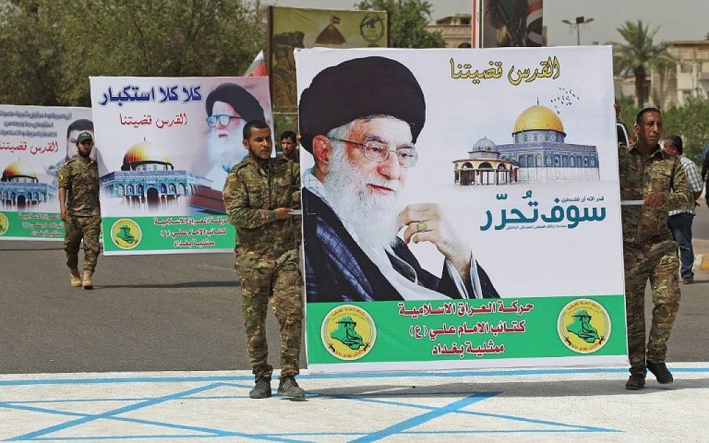 Shiite militiamen carry a poster of Iran's supreme leader, Ayatollah Ali Khamenei, while stepping on a drawing of an Israeli flag during a Jerusalem Day rally in the Iraqi capital Baghdad, June 8, 2018. (AFP/Ahmad Al-Rubaye)
