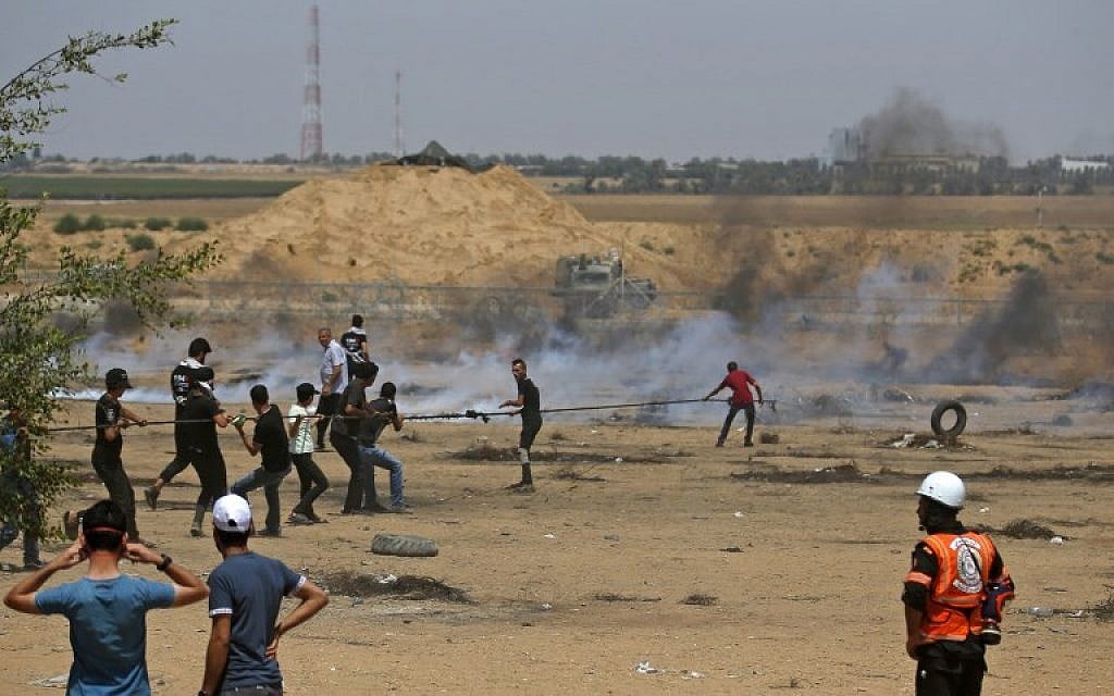Palestinians pull on a cable tied to a barbed-wire fence as they try to pull down a section of the fence with Israel, during border clashes east of Khan Younis in the southern Gaza Strip, on June 8, 2018. (AFP Photo/Said Khatib)