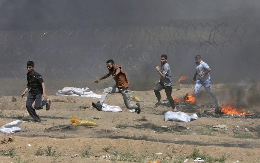 Illustrative. Palestinians run near the barbed-wire fence with Israel during clashes following a demonstration along the border with the Gaza Strip east of Gaza City on June 8, 2018. (AFP/Mahmud Hams) Illustrative. Palestinians run near the barbed-wire fence with Israel during clashes following a demonstration along the border with the Gaza Strip east of Gaza City on June 8, 2018. (AFP/Mahmud Hams)