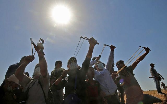 Palestinians use slingshots to hurl stones toward Israeli forces during clashes near the border with Israel, east of Khan Younis in the southern Gaza Strip, on June 8, 2018. (AFP Photo/Said Khatib)