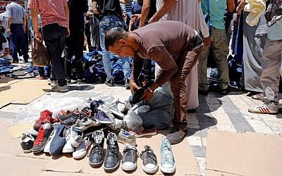 Jordanians buy second-hand shoes in an open air market in central Amman on June 8, 2018. (AFP Photo/Ahmad Gharabli)