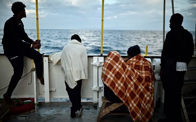 In this photo taken on May 14, 2018 migrants look at the coastline as they stand aboard the French rescue ship MV Aquarius, off the coast of Sicily. (AFP PHOTO / LOUISA GOULIAMAKI) In this photo taken on May 14, 2018 migrants look at the coastline as they stand aboard the French rescue ship MV Aquarius, off the coast of Sicily. (AFP PHOTO / LOUISA GOULIAMAKI)
