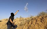 Illustrative: A masked Palestinian man launches a balloon loaded with flammable materials toward Israel from the southern Gaza town of Rafah on June 17, 2018. (AFP Photo/Said Khatib)
