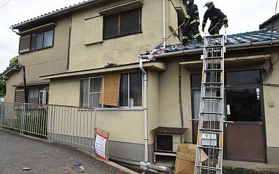 Firefighters check a house damaged by an earthquake in Ibaraki City, north of Osaka prefecture on June 18, 2018. (AFP PHOTO / JIJI PRESS / STR)