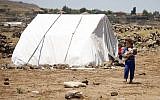 A displaced Syrian girl from the Daraa province fleeing shelling by pro-government forces carries a toddler in a makeshift camp in the province of Quneitra, southwestern Syria, near the border with the Golan Heights, on June 22, 2018. (AFP/Mohamad Abazeed)