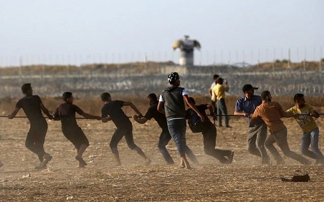Illustrative. Palestinians pull on a metal cable as they try to take down a section of barbed wire on the border fence with Israel, east of Khan Younis in the southern Gaza Strip, on June 22, 2018. (AFP Photo/Said Khatib) Illustrative. Palestinians pull on a metal cable as they try to take down a section of barbed wire on the border fence with Israel, east of Khan Younis in the southern Gaza Strip, on June 22, 2018. (AFP Photo/Said Khatib)