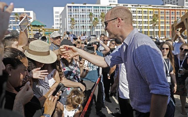 Britain's Prince William, right, reaches out to a person as reporters and beach-goers swarm around him, during a visit to a beach in the coastal Mediterranean city of Tel Aviv, June 26, 2018. (Menahem KAHANA/AFP)