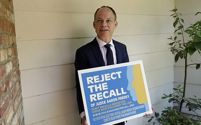 Judge Aaron Persky poses for a photo with a sign opposing his recall in Los Altos Hills, California, May 15, 2018. (Jeff Chiu/AP) Judge Aaron Persky poses for a photo with a sign opposing his recall in Los Altos Hills, California, May 15, 2018. (Jeff Chiu/AP)