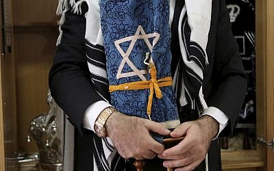 In this May 30, 2018 photo, Rabbi Arie Zeev Raskin, the leader of Cyprus' 3,500-strong Jewish community, holds a rare 200 year-old Torah scroll that comes from Germany at a Synagogue inside Cyprus' Jewish Community Center in the town of Larnaca. (AP Photo/Petros Karadjias)