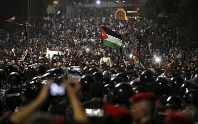 Jordanian protesters shout slogans and raise a national flag during a demonstration outside the Prime Minister's office in the capital Amman early Monday, June 4, 2018. (AP/Raad Adayleh)