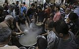 In this Thursday, May 31, 2018 photo, free porridge is distributed to the poor during the holy fasting month of Ramadan in Gaza City. (AP Photo/Adel Hana)