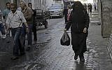 In this May 31, 2018, photo, Samia Hassan, walks with free porridge distributed by Walid al-Hattab, who cooks the free meals as Ramadan charity, in Gaza City. (AP Photo/Adel Hana)