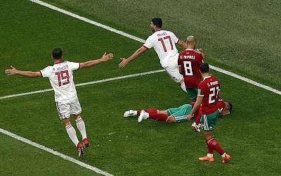 Iranian Players celebrate as Morocco's Aziz Bouhaddouz lies on the pitch after scoring an own goal during the group B match between Morocco and Iran at the 2018 soccer World Cup in the St. Petersburg Stadium in St. Petersburg, Russia, Friday, June 15, 2018. (AP Photo/Darko Vojinovic)