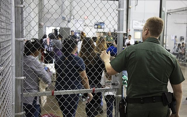 In this photo a US Border Patrol agent watches as people who've been taken into custody related to cases of illegal entry into the United States, stand in line at a facility in McAllen, Texas, Sunday, June 17, 2018. (US Customs and Border Protection's Rio Grande Valley Sector via AP) In this photo a US Border Patrol agent watches as people who've been taken into custody related to cases of illegal entry into the United States, stand in line at a facility in McAllen, Texas, Sunday, June 17, 2018. (US Customs and Border Protection's Rio Grande Valley Sector via AP)