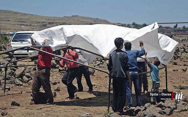 This June 22, 2018 photo provided by Nabaa Media, a Syrian opposition media outlet, shows people who fled from Daraa setting up a tent in the village of Bregia, near the Syria-Israel border, southern Syria. (Nabaa Media, via AP) This June 22, 2018 photo provided by Nabaa Media, a Syrian opposition media outlet, shows people who fled from Daraa setting up a tent in the village of Bregia, near the Syria-Israel border, southern Syria. (Nabaa Media, via AP)