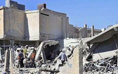 This Tuesday, June 26, 2018 photo provided by Nabaa Media, a Syrian opposition media outlet, shows civilians inspecting damaged buildings that were hit by Syrian government forces bombardment, in Daraa, southern Syria (Nabaa Media, via AP)