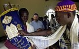 Illustrative: A Ugandan Abayudaya Jew leans forward to touch a Torah scroll carried by Enosh Keki Mainah (left) during Shabbat services at the synagogue in Nabugoya, Uganda, on March 3, 2002. (AP Photo/Sayyid Azim/File)