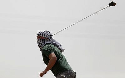 A demonstrator throws a stone at Israeli soldiers during clashes in the West Bank village of Nebi Saleh near Ramallah, April 21, 2017. (AP Photo/Majdi Mohammed)