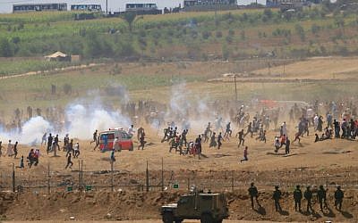 Palestinians run from tear gas fired by Israeli soldiers during clashes along the Gaza Strip border fence on June 8, 2018. (AP Photo/Ariel Schalit)