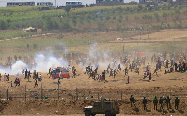 Palestinians run from tear gas fired by Israeli soldiers during clashes along the Gaza Strip border fence on June 8, 2018. (AP Photo/Ariel Schalit)