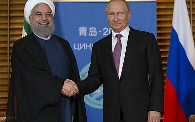 Russian President Vladimir Putin, right, and Iranian President Hassan Rouhani shake hands during their meeting in Qingdao, China, Saturday, June 9, 2018.  (AP Photo/Alexander Zemlianichenko, Pool)