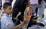 In this May 16, 2018 file photo, a boy buys a Ramadan decoration depicting the Egyptian Liverpool soccer player Mohamed Salah in Sayyeda Zeinab market in preparation for the holy month of Ramadan, in Cairo, Egypt. (AP Photo/Amr Nabil, File)