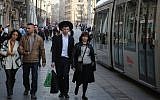 A young Israeli secular couple walks next to an ultra-Orthodox couple as the light rail goes by on Jaffa road in central Jerusalem on January 22, 2014. (Hadas Parush/Flash 90)