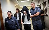 Border Police officer Ben Deri, who was later convicted of killing a 17-year-old Palestinian teenager during riots in the West Bank town of Betunia in 2014, covers his face as he walks into a hearing at the Jerusalem District Court on December 7, 2014. (Miriam Alster/Flash90)