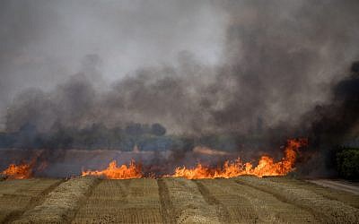 Illustrative: Firefighters extinguish a fire in a wheat field caused by kites flown by Palestinians from the Gaza Strip into Israel, May 30, 2018. (Yonatan Sindel/Flash90)
