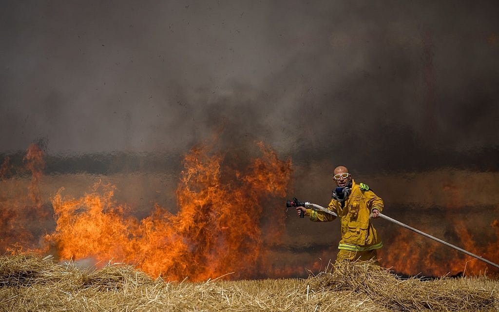 Israeli firefighters extinguish a fire in a wheat field caused from kites flown by Palestinians, near the border with the Gaza Strip, May 30, 2018. (Yonatan Sindel/Flash90)