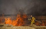 Israeli firefighters extinguish a fire in a wheat field caused from kites flown by Palestinians, near the border with the Gaza Strip, May 30, 2018. (Yonatan Sindel/Flash90)