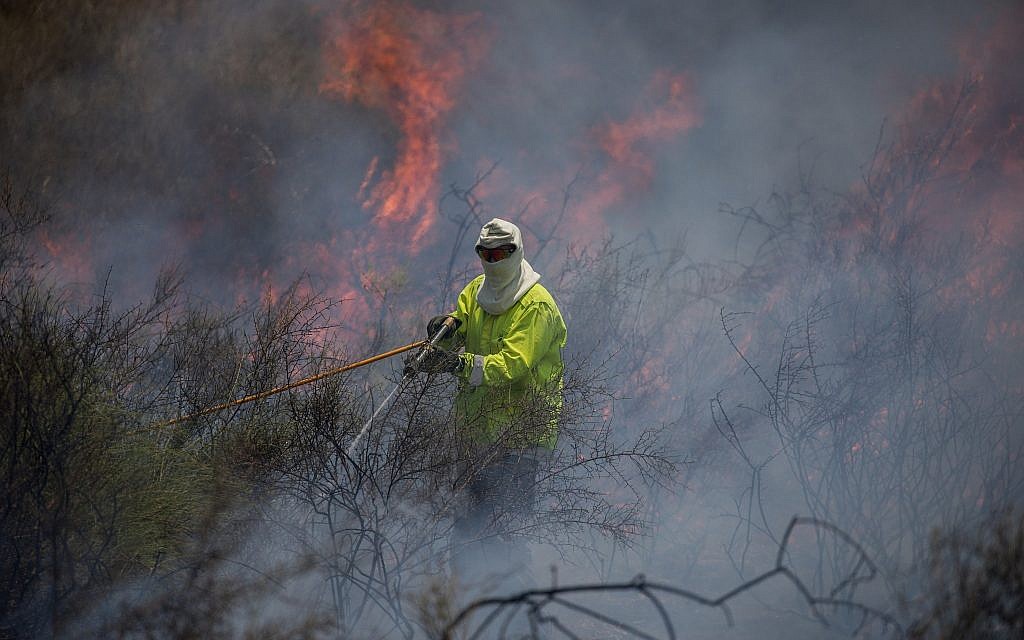 Firefighters extinguish a fire in a field caused from kites flown by Palestinians in the Gaza Strip, near the border with the Gaza Strip, June 5, 2018. (Yonatan Sindel/Flash90)