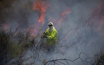 Firefighters extinguish a fire in a field caused from kites flown by Palestinians in the Gaza Strip, near the border with the Gaza Strip, June 5, 2018. (Yonatan Sindel/Flash90)