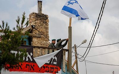 Border Police remove an Israeli flag hanging from a home slated for demolition in the Netiv Ha'avot outpost on June 13, 2018. (Gershon Elinson/Flash90)