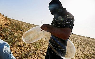 A masked Palestinian prepares a balloon that will be attached to flammable materials to be launched into Israel near the Israeli Gaza border, in Rafah in the southern Gaza Strip on June 17, 2018. (Abed Rahim Khatib/Flash90)