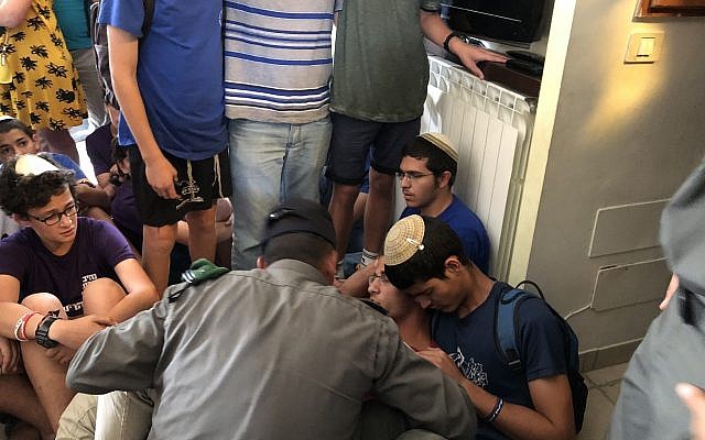 A border police officer asks one of the child residents of a home, built illegally in the Netiv Ha'avot outpost in the Gush Etzion area of the West Bank, to leave the premises on June 12, 2018. (Luke Tress/Times of Israel)